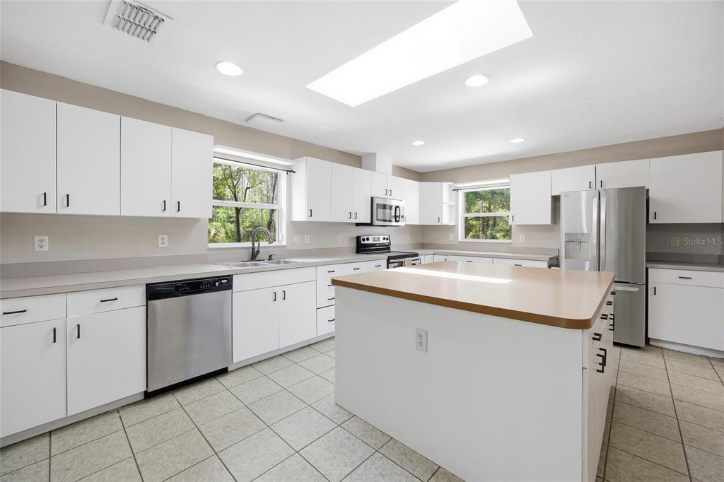 A kitchen with white cabinets, stainless steel appliances, a center island, and tiled flooring — 7050 NE STATE ROAD 121, WILLISTON, FL