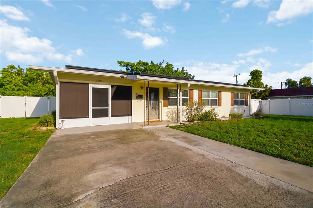 A single-story house with a screened-in porch, a concrete driveway, and a white fence — 4704 PARK ACRES DRIVE, BRADENTON, FL