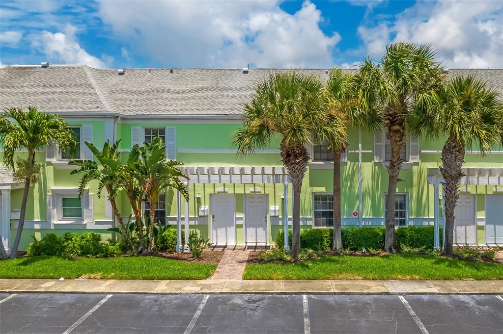 A two-story lime green townhouse exterior with palm trees and a paved parking lot — 4779 COQUINA KEY DRIVE SE, ST PETERSBURG, FL