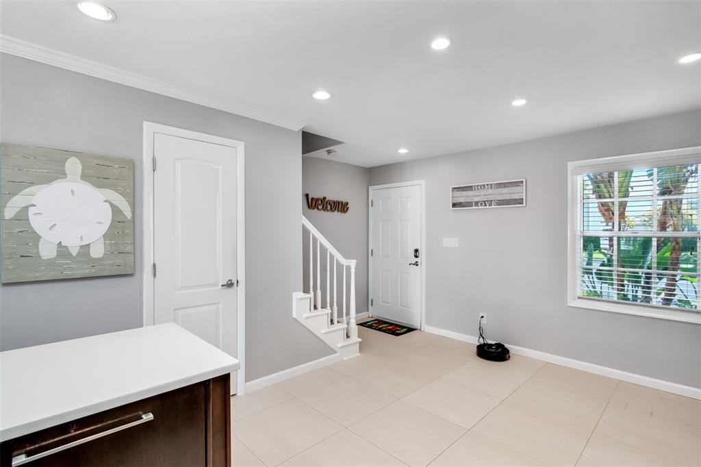 An entryway with light gray walls, tile flooring, a staircase, and a white front door — 4779 COQUINA KEY DRIVE SE, ST PETERSBURG, FL
