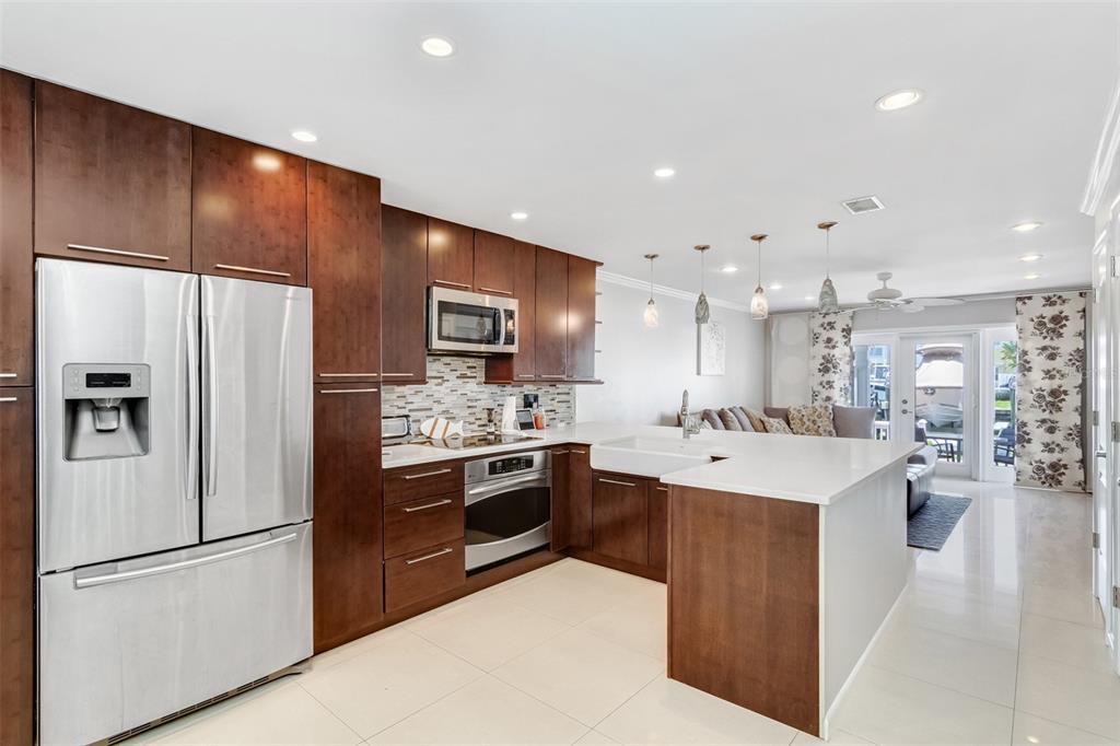 A modern kitchen features dark wood cabinets, stainless steel appliances, and a white quartz island — 4779 COQUINA KEY DRIVE SE, ST PETERSBURG, FL