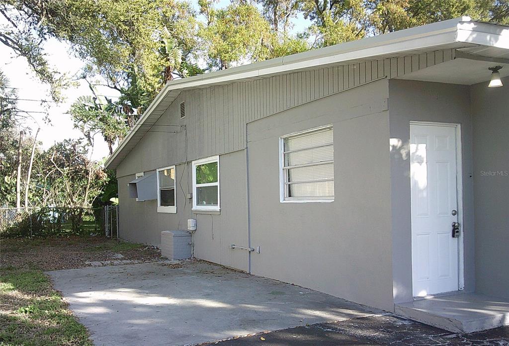 The exterior of a gray building features a white door and a cracked asphalt driveway — 1060 65TH STREET S, ST PETERSBURG, FL