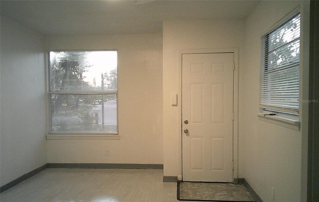 The exterior of a gray house features a white door, two windows, and a concrete patio — 1060 65TH STREET S, ST PETERSBURG, FL