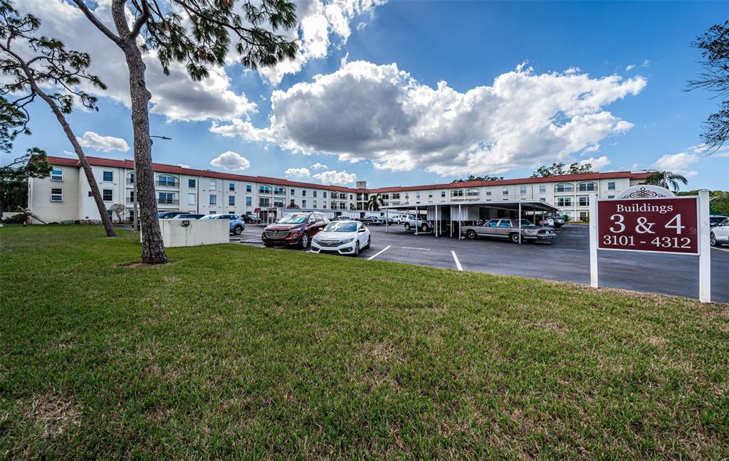 A multi-story apartment building with a parking lot and a sign for buildings 3 and 4 — 2700 BAYSHORE BOULEVARD UNIT 3208, DUNEDIN, FL