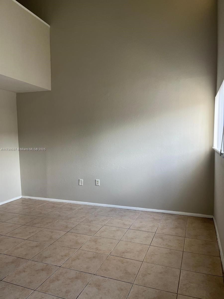 An empty room features beige walls, a high ceiling, and light-colored tile flooring — 4002 Dolomite # A, Orlando FL 32839, ORLANDO, FL