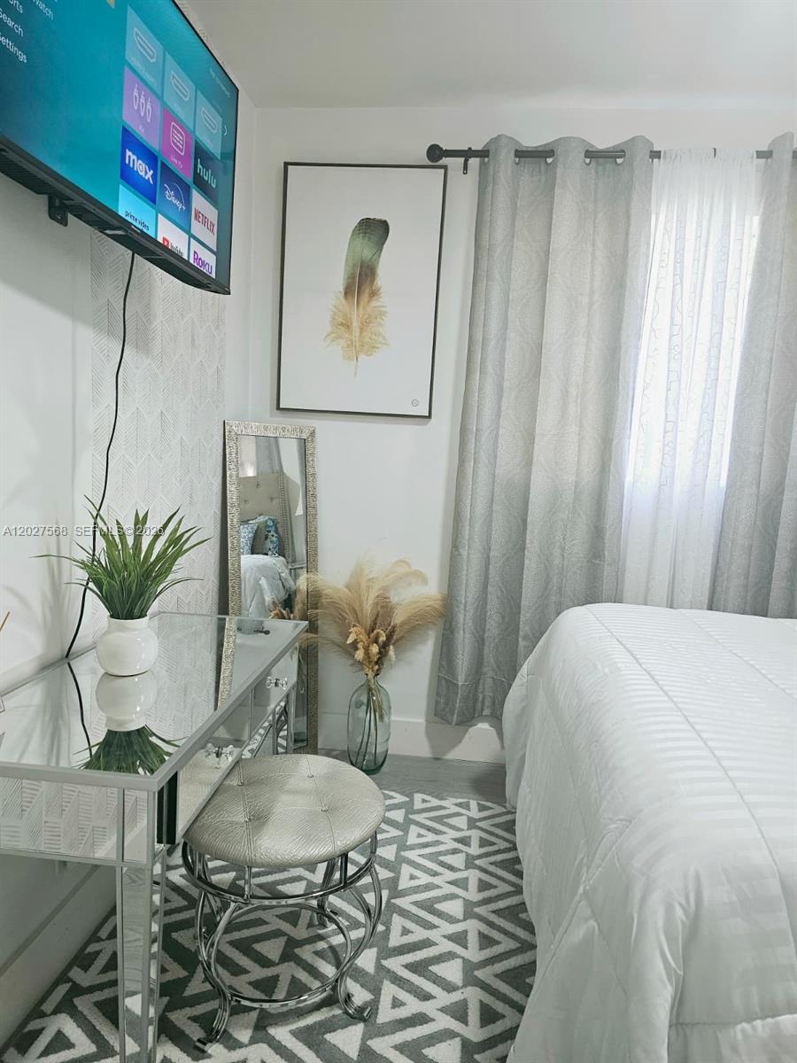 A bedroom features a mirrored vanity, a wall-mounted television, and a bed with grey curtains — 4890 NW 7th St # 2, Plantation FL 33317, PLANTATION, FL