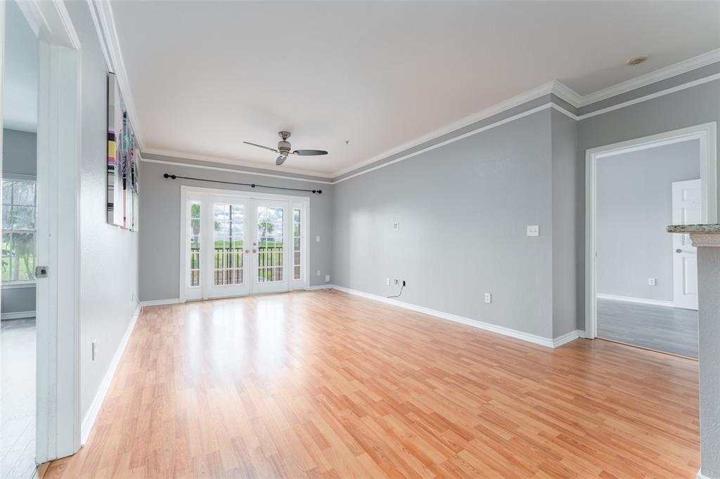 An empty room with light wood flooring, gray walls, a ceiling fan, and glass French doors — 4306 BAYSIDE VILLAGE DRIVE UNIT 202, TAMPA, FL