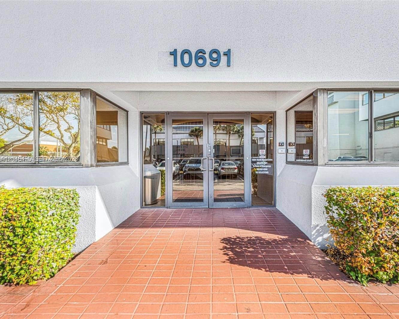The exterior entrance of a commercial building features glass double doors and a tiled walkway — 10691 SW 88th St, Miami FL 33176, MIAMI, FL