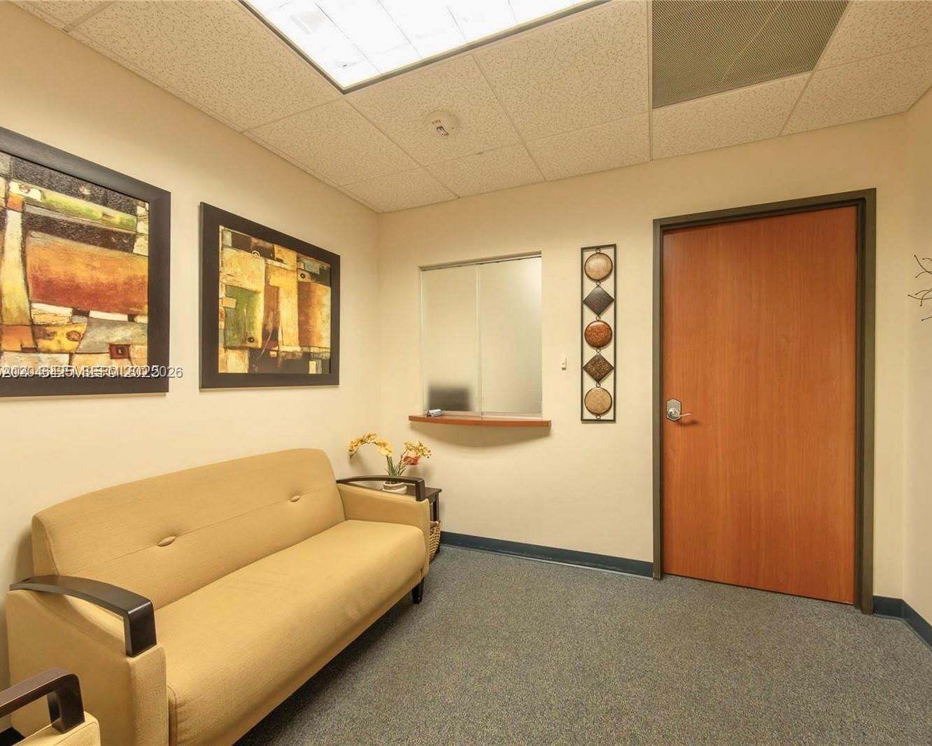 A waiting room features a tan sofa, two framed abstract paintings, and a wooden door — 10691 SW 88th St, Miami FL 33176, MIAMI, FL