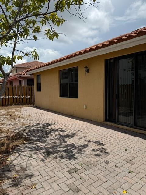 A paved patio sits beside a yellow stucco house with a tiled roof — MIAMI, FL