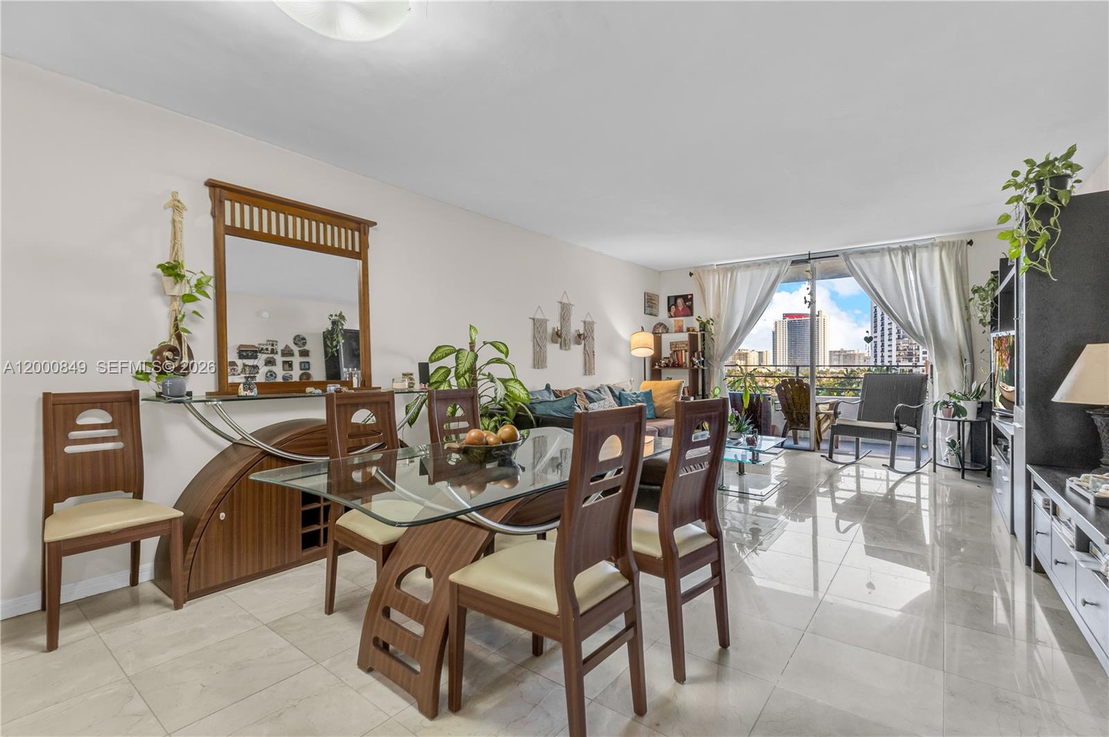 A dining and living area features a glass-top table, tile flooring, and a balcony view — 600 Three Islands Blvd # 618, Hallandale Beach FL 33009, HALLANDALE BEACH, FL