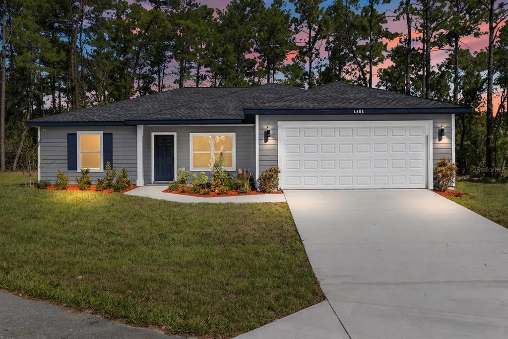A single-story house with light blue siding, a white garage door, and a concrete driveway — 8040 SW 133RD LANE, OCALA, FL