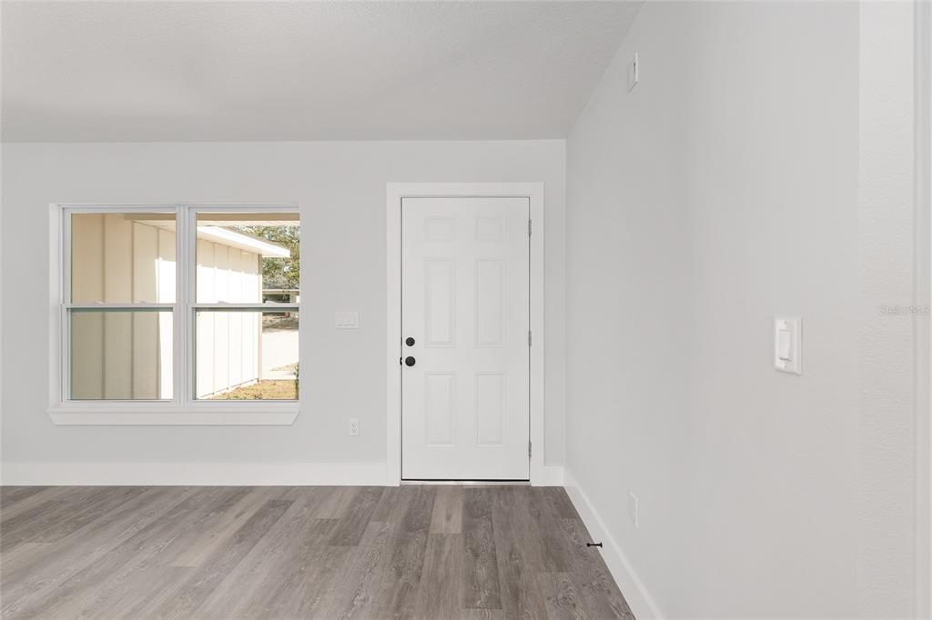 A gray house exterior features a blue front door, a garage, and red mulch landscaping — 8040 SW 133RD LANE, OCALA, FL
