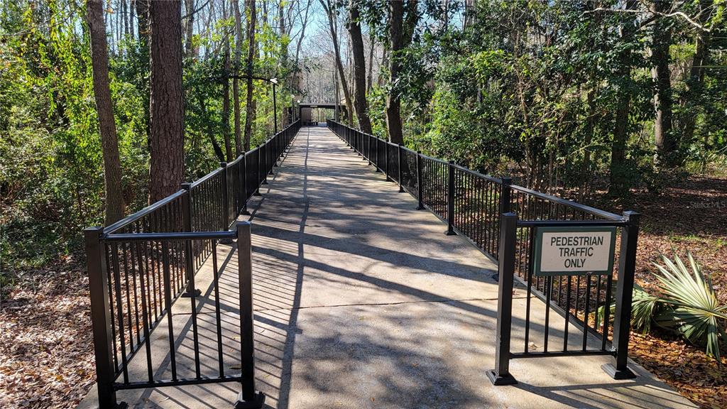 A concrete pedestrian walkway with black metal railings leads through a wooded area — 2301 PARK AVENUE UNIT #300, ORANGE PARK, FL