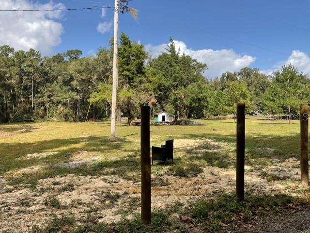A grassy lot features a small shed, a lone chair, and several wooden fence posts — 5542 SW 57TH AVENUE, GAINESVILLE, FL