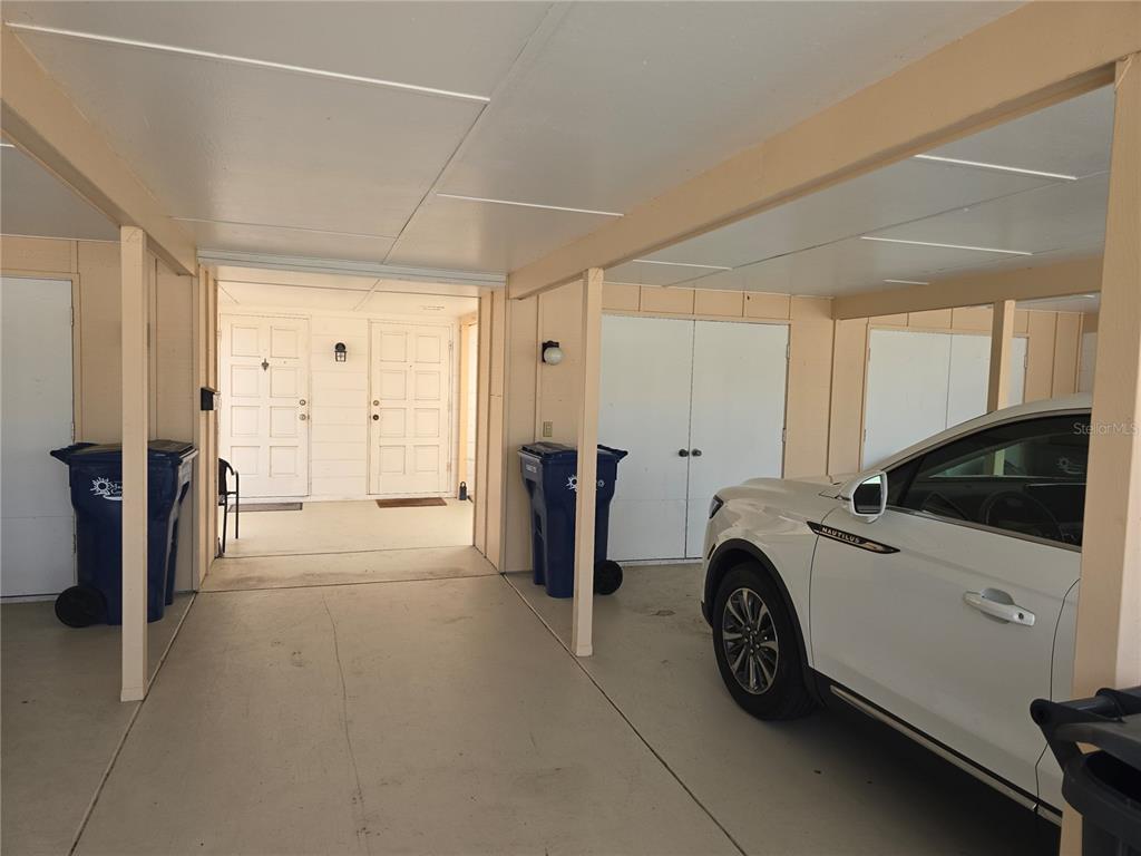 A covered carport features a concrete floor, two blue trash bins, and a white SUV — 5064 LIVE OAK CIR UNIT 5064, BRADENTON, FL