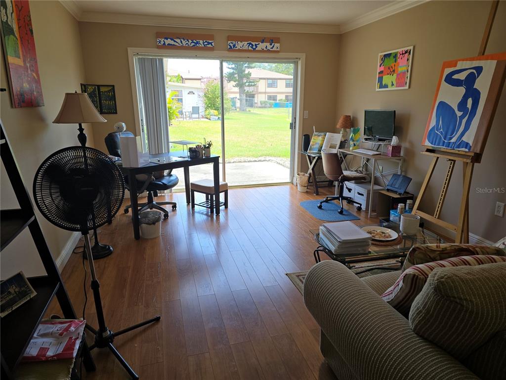 A living room with wood-look flooring, two desks, an easel, and a sliding glass door — 5064 LIVE OAK CIR UNIT 5064, BRADENTON, FL