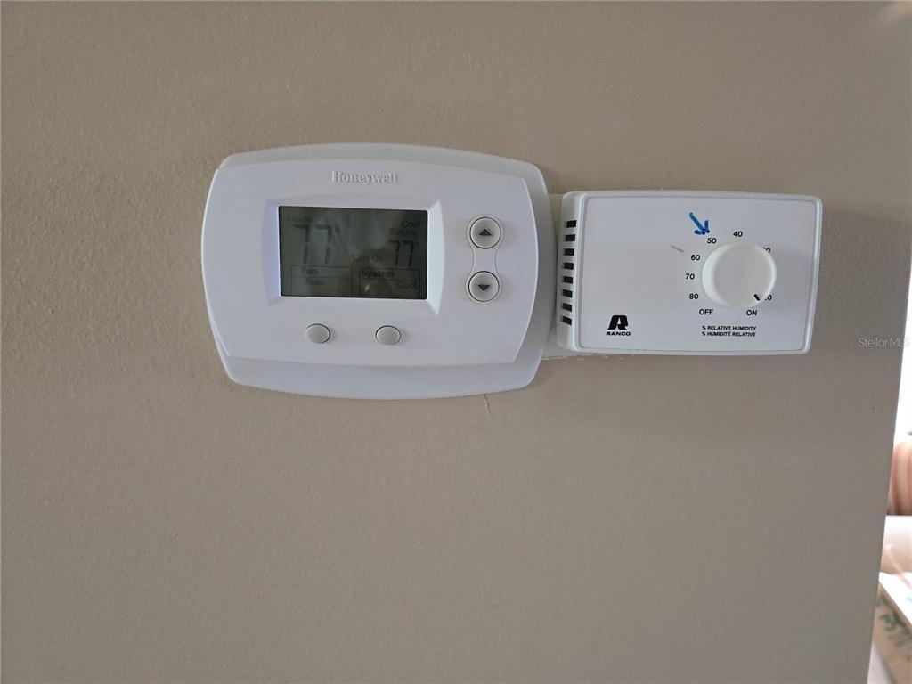 A Honeywell thermostat and a Ranco humidistat are mounted side-by-side on a beige wall — 5064 LIVE OAK CIR UNIT 5064, BRADENTON, FL