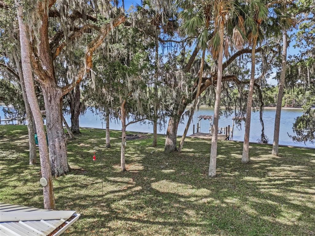 A grassy yard with mature trees and Spanish moss overlooks a river with a dock — 4368 N OCEAN SHORE BLVD, PALM COAST, FL