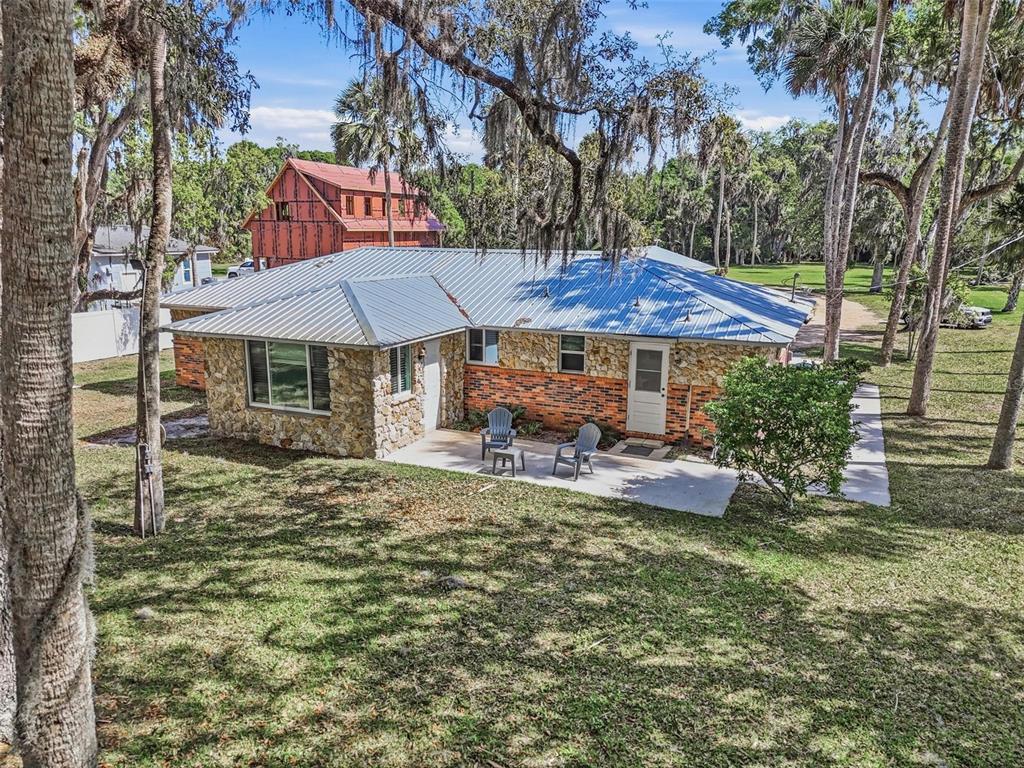 A single-story house with a metal roof and stone and brick exterior sits on a lawn — 4368 N OCEAN SHORE BLVD, PALM COAST, FL