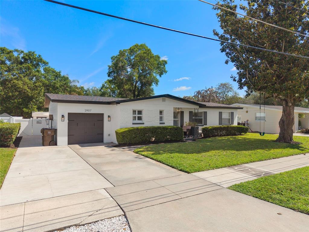 A single-story white brick house with a dark garage door and a front lawn — 2907 VINE STREET, ORLANDO, FL
