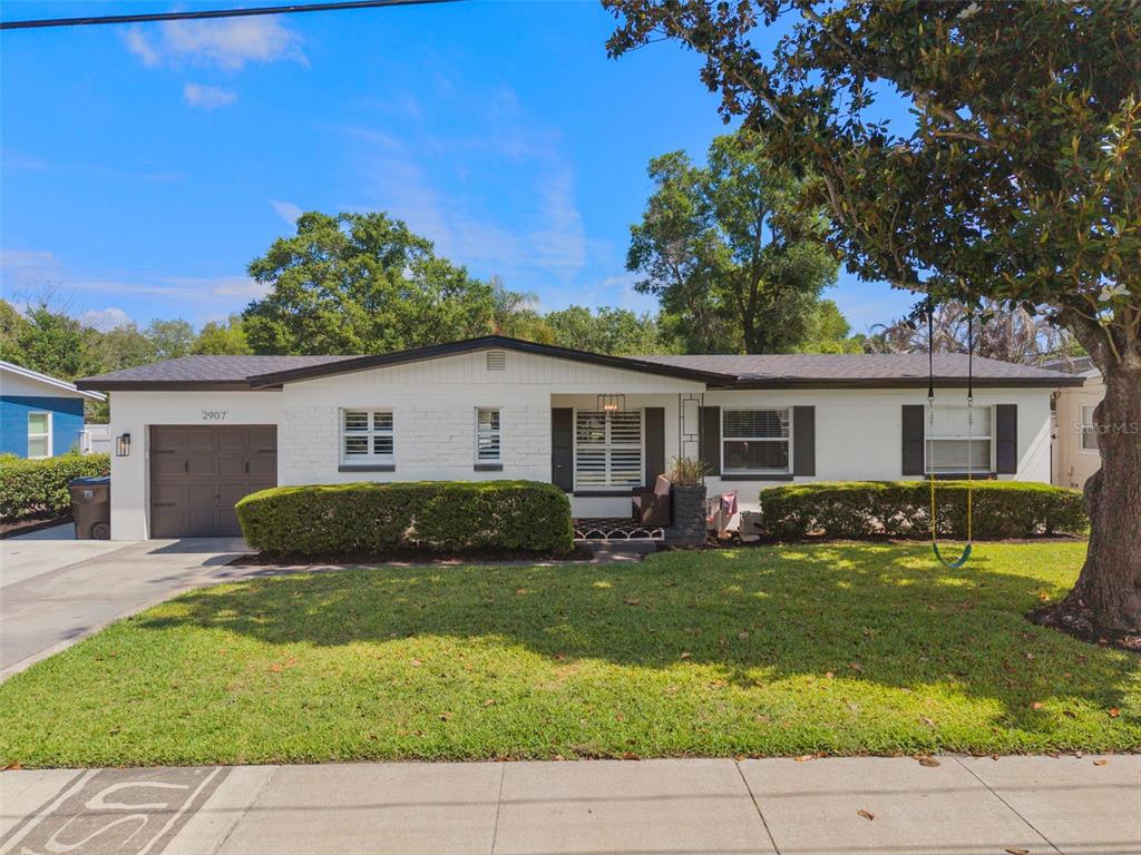 A single-story white brick house with a dark garage door and a front lawn — 2907 VINE STREET, ORLANDO, FL