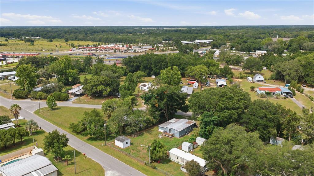 An aerial view shows several houses and outbuildings scattered across a wooded, grassy residential area — 14615 SE 87TH TERRACE ROAD, SUMMERFIELD, FL