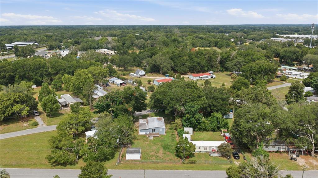 An aerial view shows several small houses and outbuildings situated on a large, tree-filled lot — 14615 SE 87TH TERRACE ROAD, SUMMERFIELD, FL