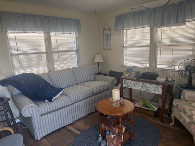 A living room features a striped sofa, a round wooden table, and windows with blinds — 7428 ARBELA STREET, PORT CHARLOTTE, FL