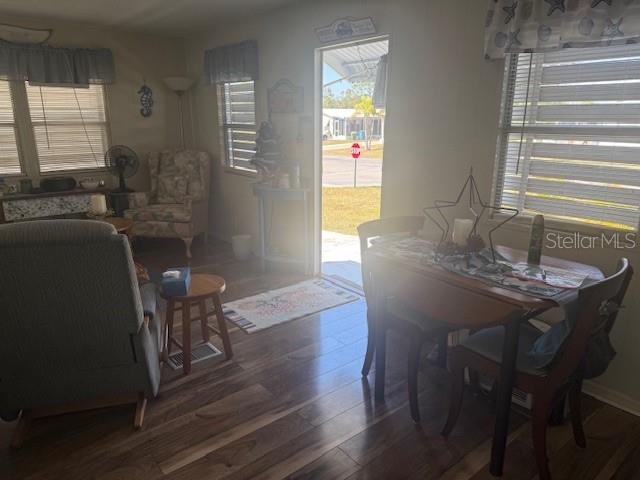 A living and dining area with wood-look flooring, a recliner, and an open exterior door — 7428 ARBELA STREET, PORT CHARLOTTE, FL