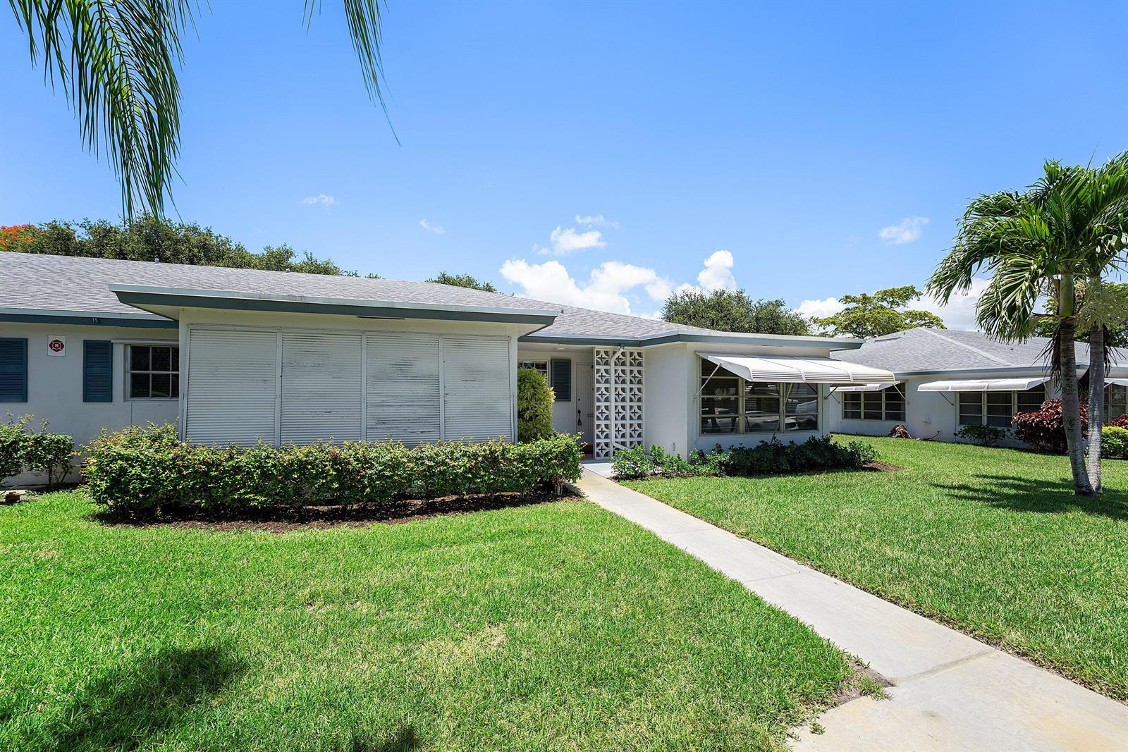 A single-story house with white siding, a concrete walkway, and a decorative breeze block screen — 1210 S Drive Circle # D, Delray Beach FL 33445, DELRAY BEACH, FL
