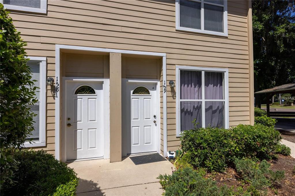 The exterior of a tan, two-story townhouse features two white front doors and large windows — 3510 SW 30TH WAY UNIT 158, GAINESVILLE, FL