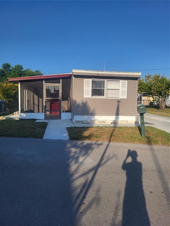 A single-story manufactured home with a screened-in porch and gray siding under a clear sky — 6580 SEMINOLE BOULEVARD UNIT 424, SEMINOLE, FL