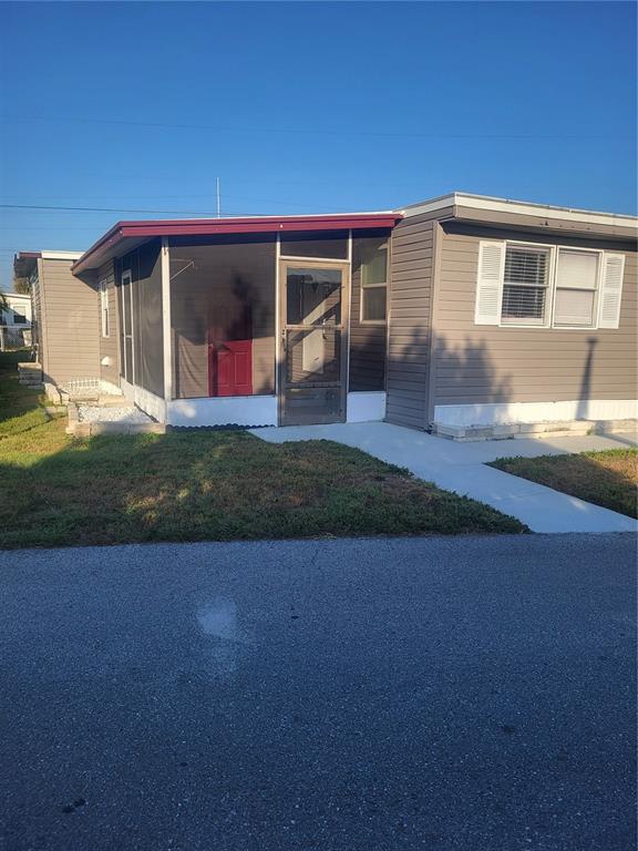 A single-story manufactured home with light brown siding and a screened-in front porch — 6580 SEMINOLE BOULEVARD UNIT 424, SEMINOLE, FL