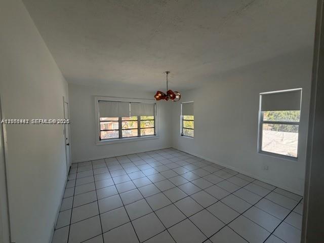 An empty room with white walls, white tile flooring, and a modern copper-toned light fixture — 2368 NW 3rd St # 4, Miami FL 33125, MIAMI, FL