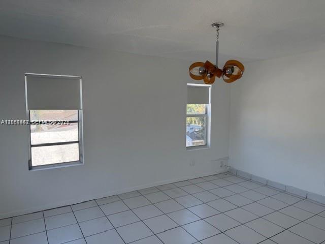 An empty room features white walls, white tile flooring, two windows, and a hanging light fixture — 2368 NW 3rd St # 4, Miami FL 33125, MIAMI, FL