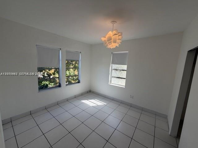 An empty room features white walls, white tile flooring, three windows, and a modern light fixture — 2368 NW 3rd St # 4, Miami FL 33125, MIAMI, FL