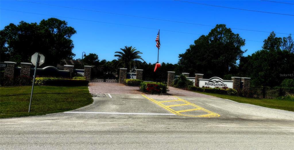 The gated entrance to Ridge Landing features stone pillars, a flag, and paved driveway — 4566 WRIGHTBROS ROAD, FROSTPROOF, FL