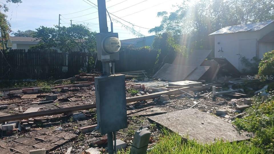 A utility pole with an electrical meter stands in a debris-filled lot with scattered wood — 6706 STOCK STREET, PORT RICHEY, FL