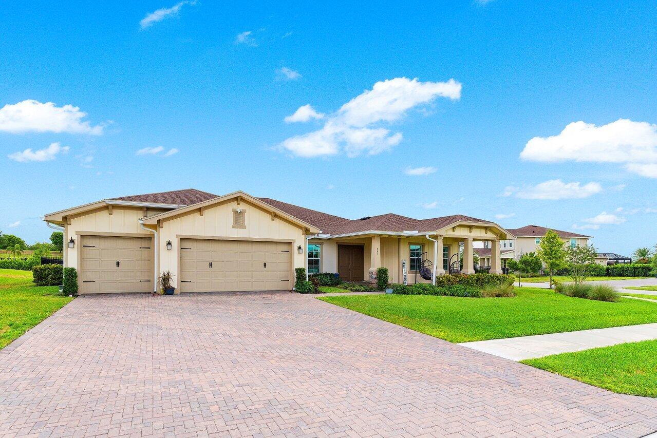 A single-story house with a beige exterior, a three-car garage, and a brick paver driveway — 962 Castaway Court, Loxahatchee FL 33470, LOXAHATCHEE, FL