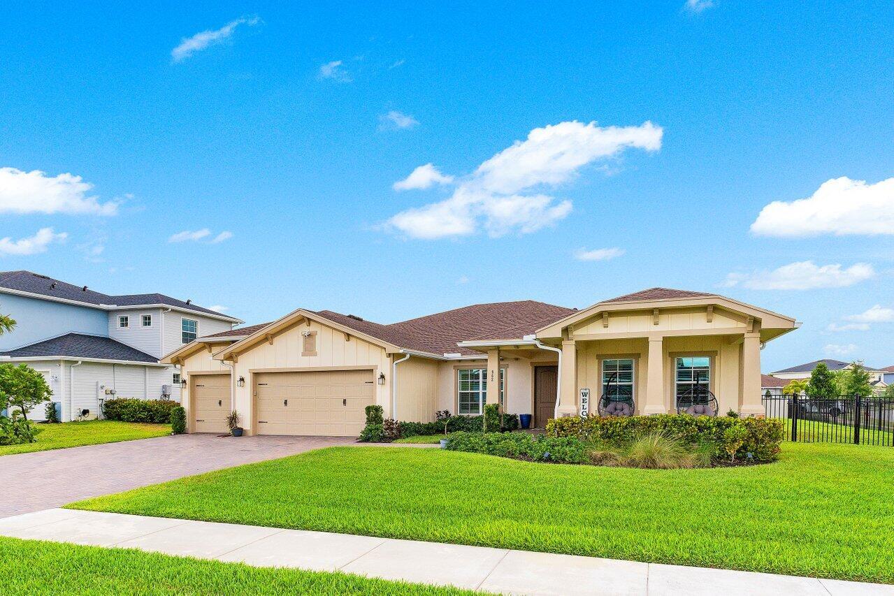 A single-story suburban house with a tan exterior, a two-car garage, and a manicured lawn — 962 Castaway Court, Loxahatchee FL 33470, LOXAHATCHEE, FL