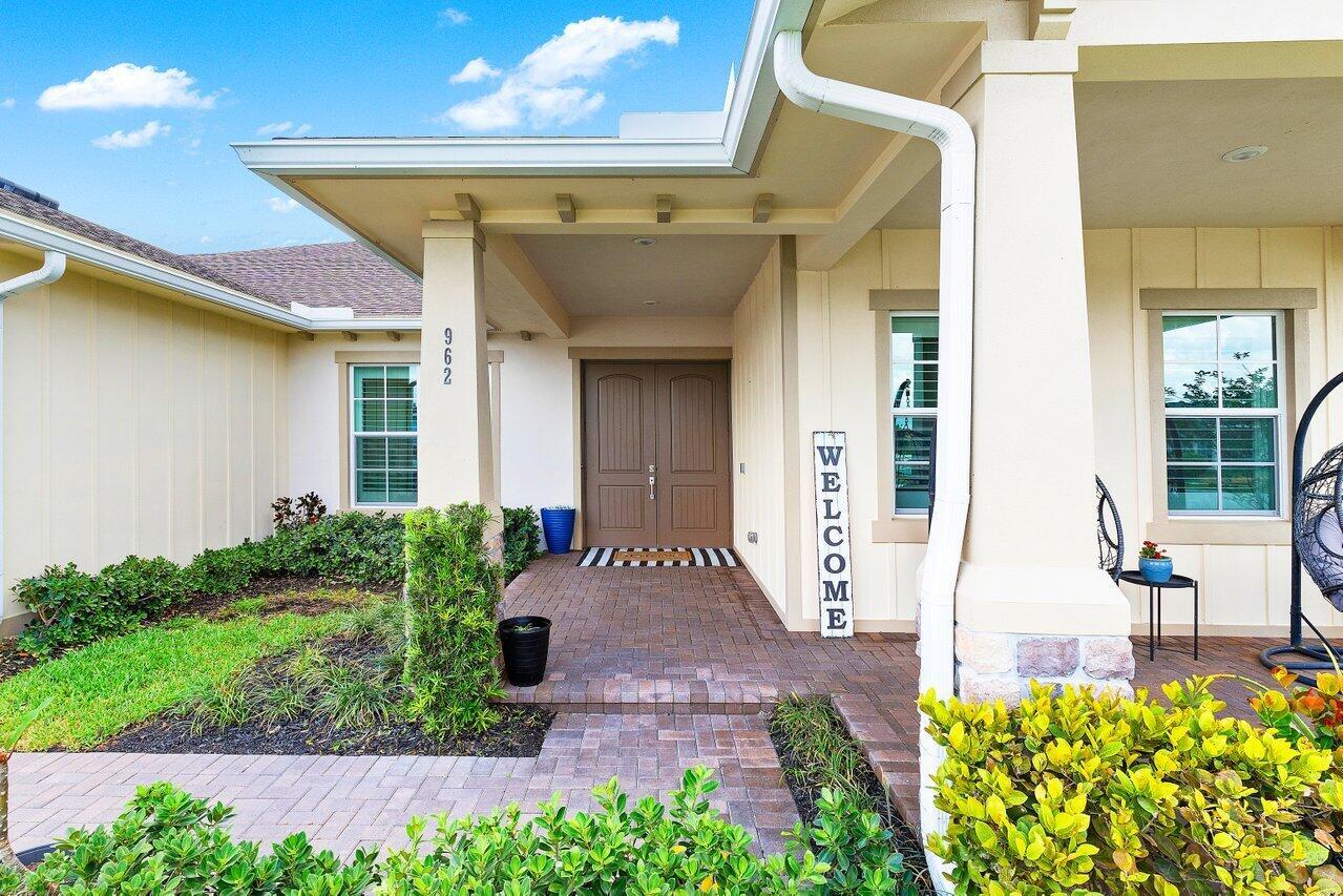 The exterior of a house features a brick walkway leading to a double-door entryway — 962 Castaway Court, Loxahatchee FL 33470, LOXAHATCHEE, FL