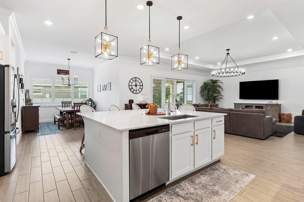 A modern open-concept kitchen features a large white island, pendant lighting, and wood-look tile flooring — 962 Castaway Court, Loxahatchee FL 33470, LOXAHATCHEE, FL