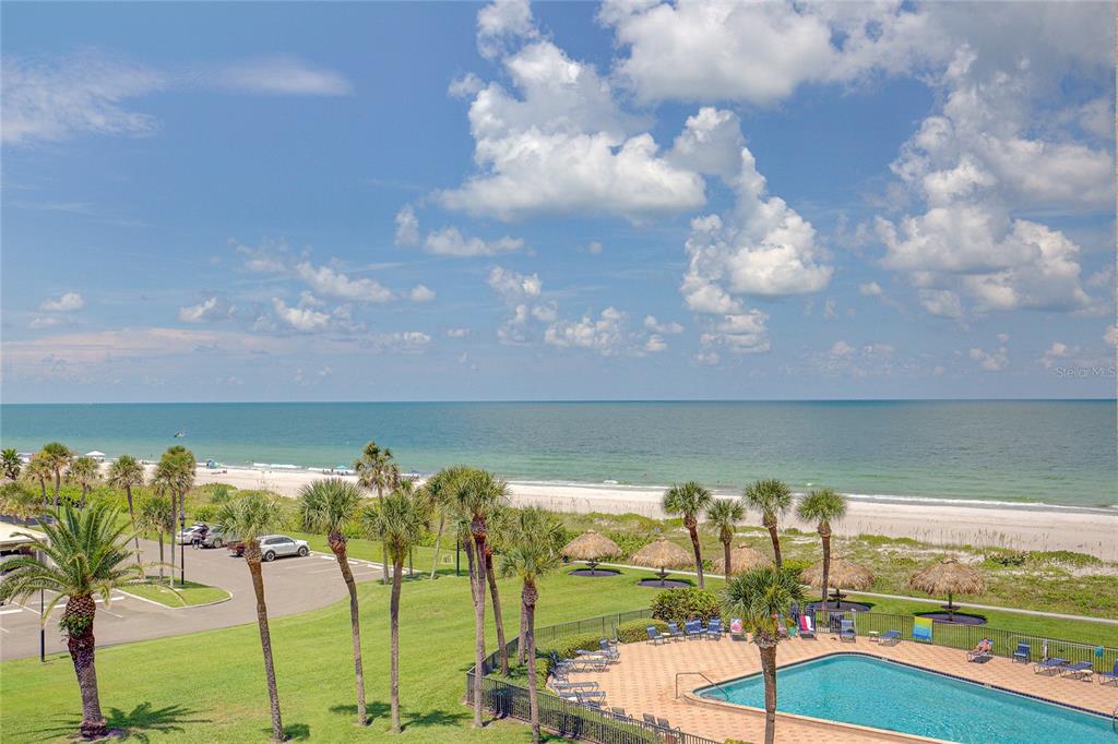 An elevated view of a beach, a swimming pool, palm trees, and a parking lot — 1460 GULF BOULEVARD UNIT 707, CLEARWATER BEACH, FL
