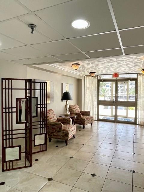 A lobby area features two patterned armchairs, a decorative room divider, and tile flooring — 1460 GULF BOULEVARD UNIT 707, CLEARWATER BEACH, FL