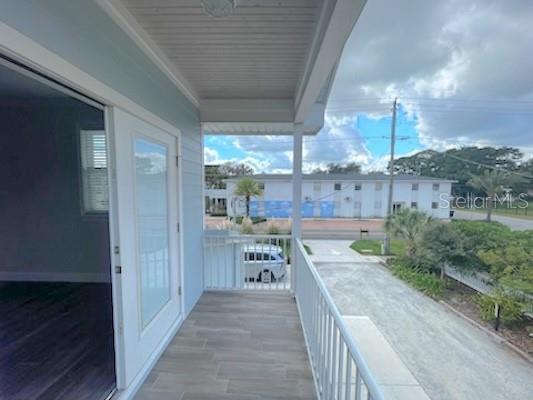 A covered balcony with tile flooring overlooks a driveway and a neighboring apartment building — 308 W BRIDGERS AVENUE, AUBURNDALE, FL