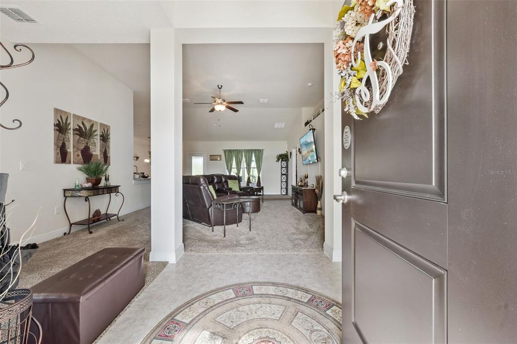 An entryway with tile flooring leads into a carpeted living room with a ceiling fan — 7521 SLOEWOOD DRIVE, LEESBURG, FL