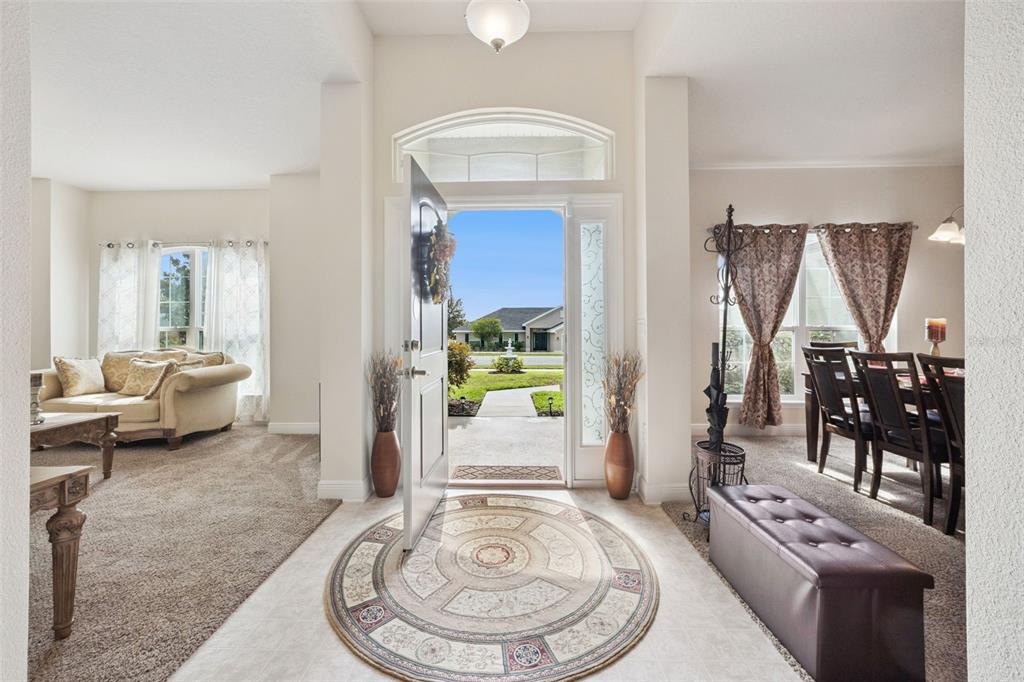 A bright entryway features a circular rug, tiled floor, and views into adjacent living areas — 7521 SLOEWOOD DRIVE, LEESBURG, FL