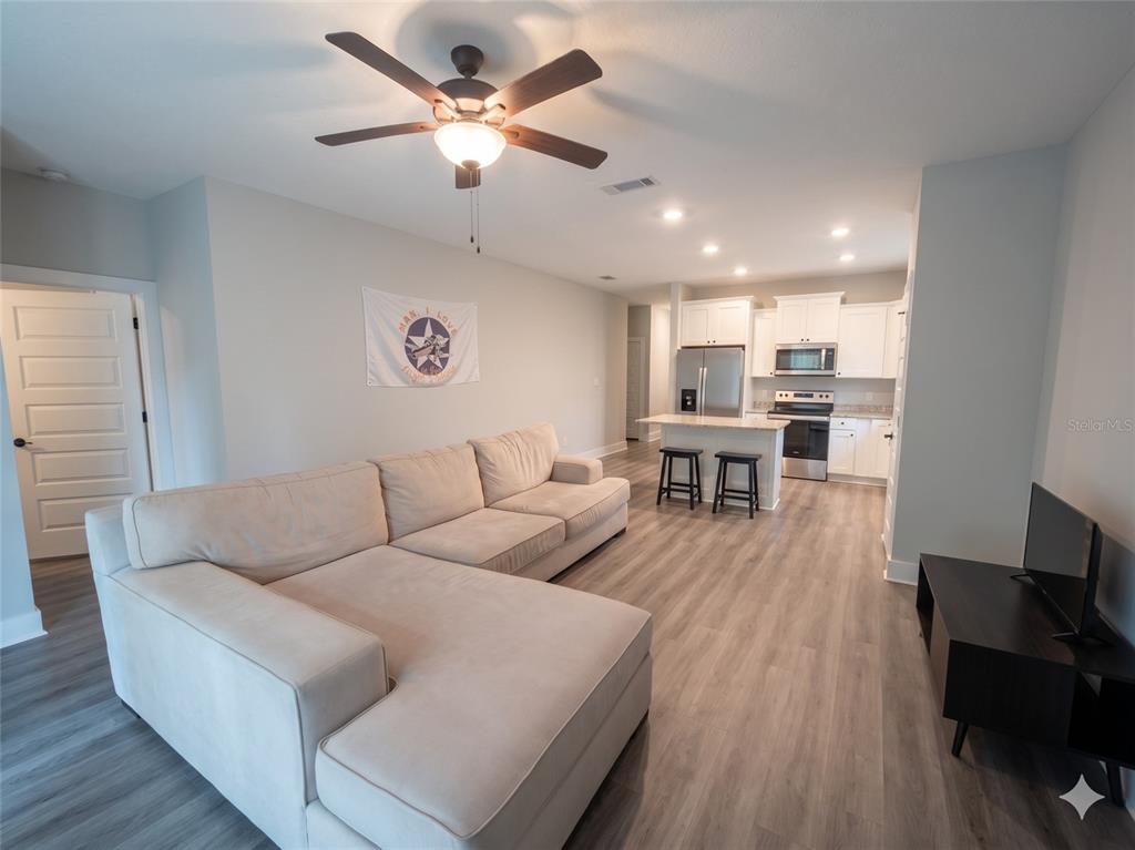 An open-concept living room features a sectional sofa, a ceiling fan, and a kitchen island — 3044 N 7TH AVENUE, MILTON, FL