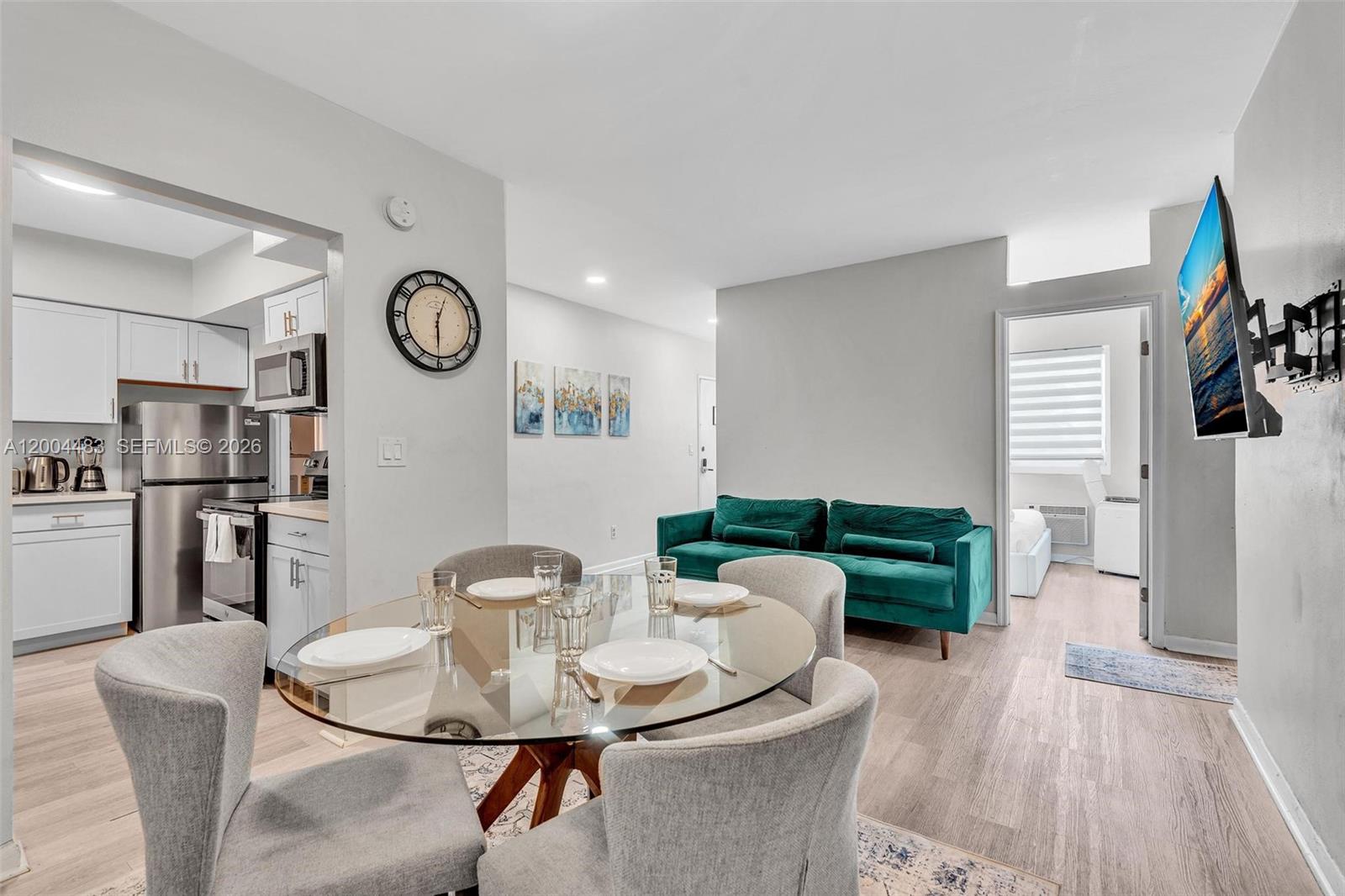 A dining area with a glass table and grey chairs sits beside a green sofa — 10006 E Bay Harbor Dr # 17, Bay Harbor Islands FL 33154, BAY HARBOR ISLANDS, FL